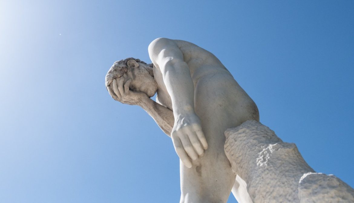 Man facepalming statue under the sun in the Tuileries garden.